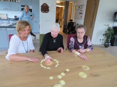 Verzorger Ria Witteveen speelt met Tovertafel samen met twee bewoners