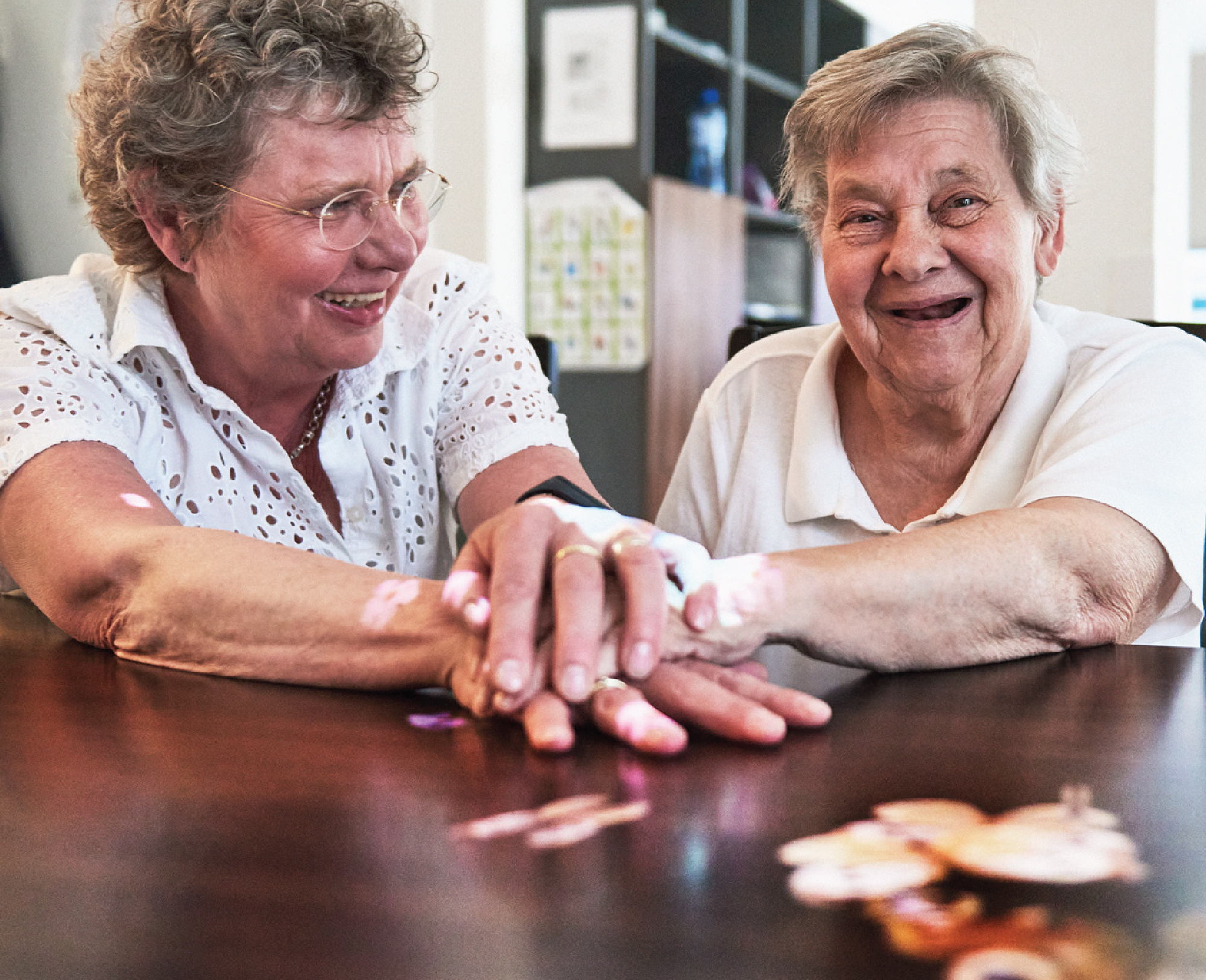 Caregiver and resident holding hands on a Tovertafel game projected on the table.